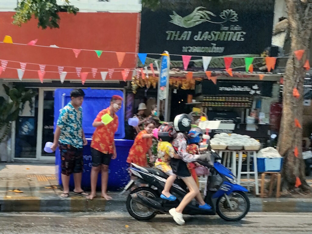 ソンクランで水をかけられているバイクの親子